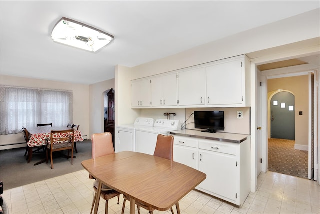 kitchen with arched walkways, washer and clothes dryer, light countertops, a baseboard heating unit, and white cabinets