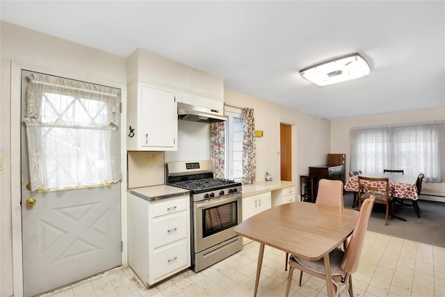 kitchen with a healthy amount of sunlight, stainless steel gas range, white cabinets, and exhaust hood