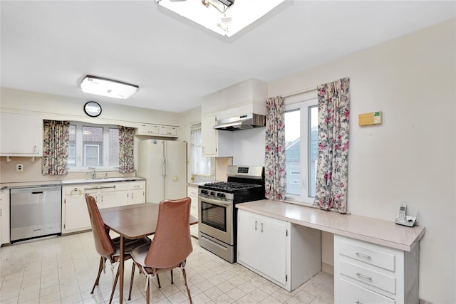 kitchen with white cabinets, appliances with stainless steel finishes, light countertops, under cabinet range hood, and a sink