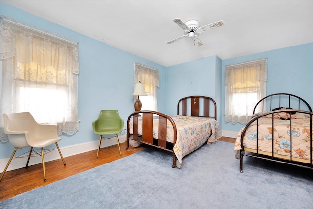 bedroom featuring wood finished floors, a ceiling fan, and baseboards