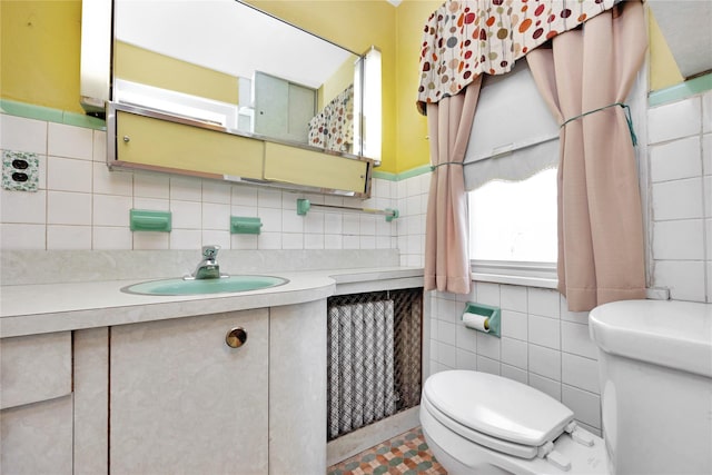 bathroom featuring vanity, toilet, and tile walls