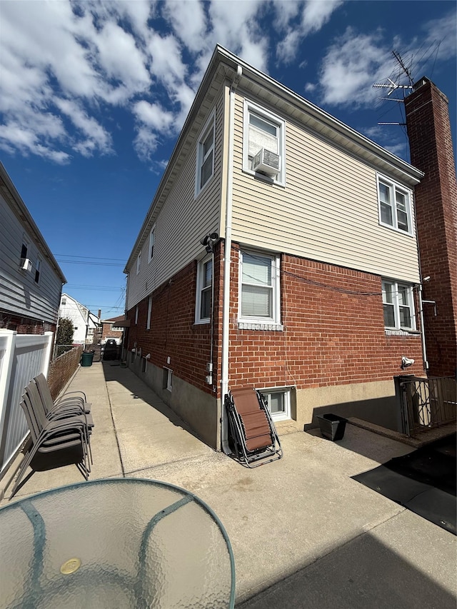 view of home's exterior featuring fence, a patio, and brick siding