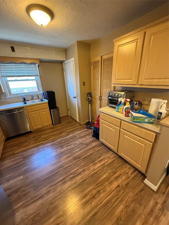 kitchen featuring a sink, dark wood-style flooring, dishwasher, and light countertops