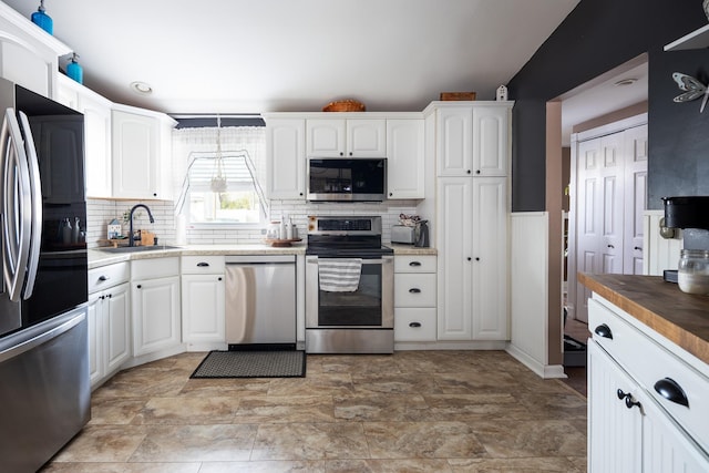 kitchen featuring stainless steel appliances, tasteful backsplash, a sink, and white cabinets