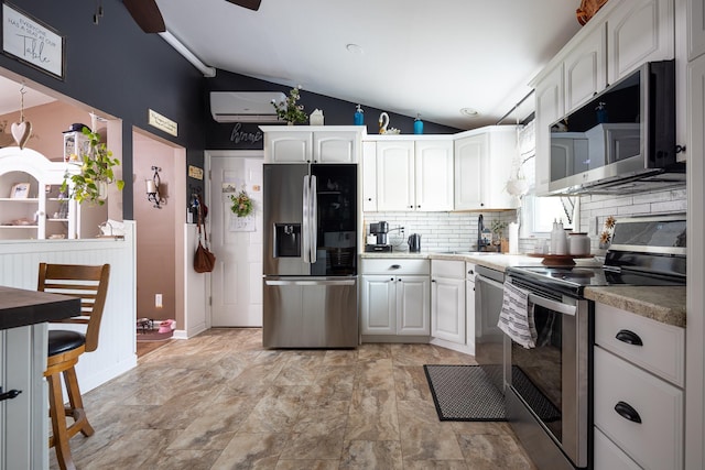 kitchen featuring white cabinetry, stainless steel appliances, a sink, and a wall mounted air conditioner