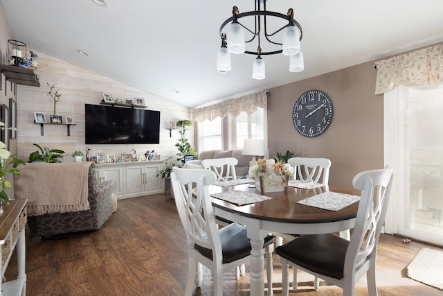 dining area with a chandelier, vaulted ceiling, and wood finished floors