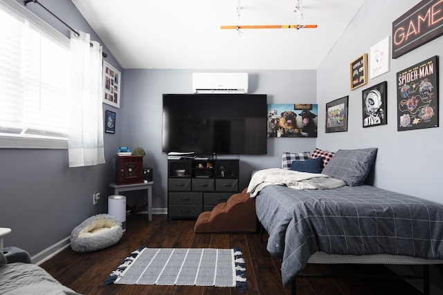 bedroom featuring multiple windows, a wall mounted AC, wood finished floors, and baseboards