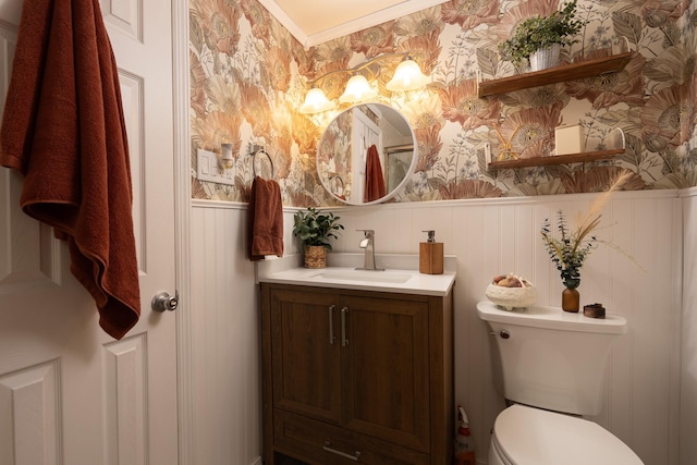 bathroom featuring a wainscoted wall, vanity, toilet, and wallpapered walls