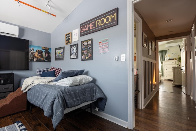 bedroom with a wall mounted air conditioner, vaulted ceiling, baseboards, and wood finished floors