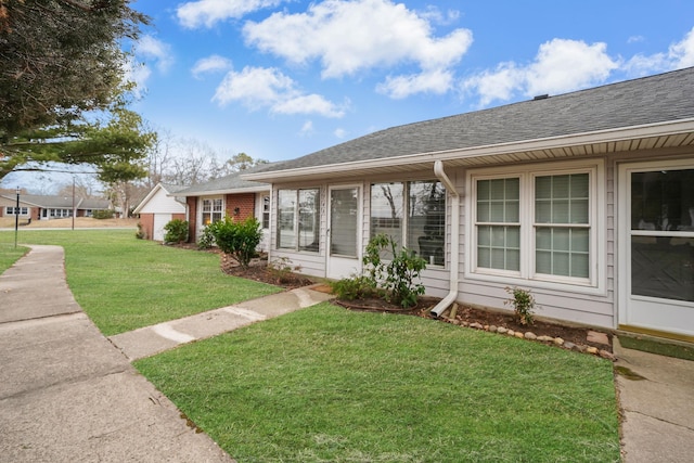 view of front of house featuring a front lawn, roof with shingles, and brick siding