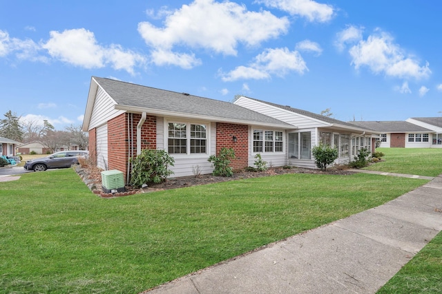 ranch-style home with roof with shingles, brick siding, and a front lawn