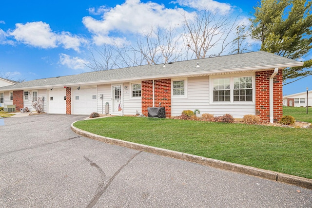 single story home featuring brick siding, roof with shingles, a garage, driveway, and a front lawn