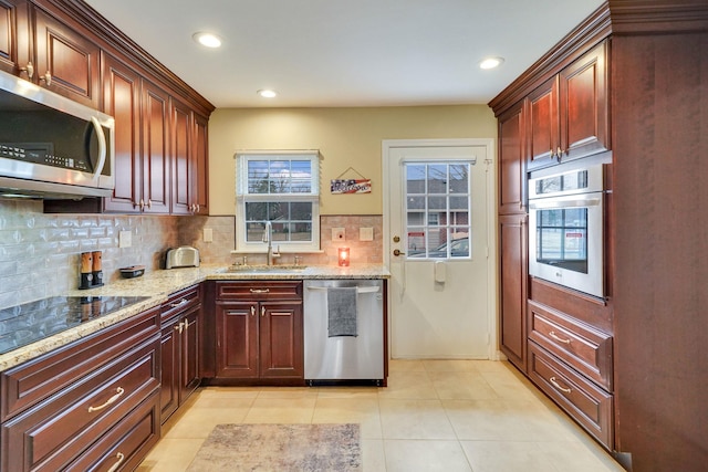 kitchen with light stone counters, tasteful backsplash, appliances with stainless steel finishes, light tile patterned flooring, and a sink