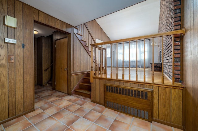 stairs featuring tile patterned flooring, wooden walls, and radiator heating unit