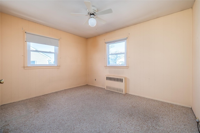 unfurnished room with carpet floors, a wealth of natural light, radiator, and ceiling fan