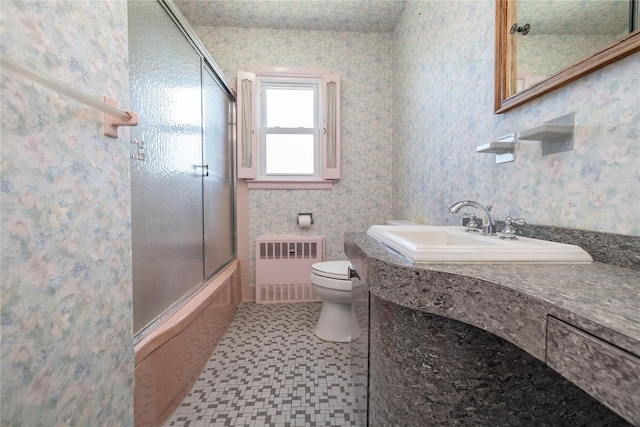 bathroom featuring radiator, toilet, combined bath / shower with glass door, vanity, and wallpapered walls