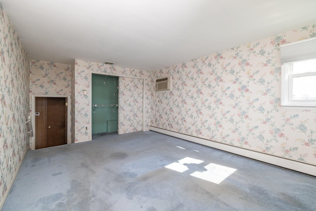 empty room featuring a baseboard radiator, carpet flooring, visible vents, a wall mounted AC, and wallpapered walls