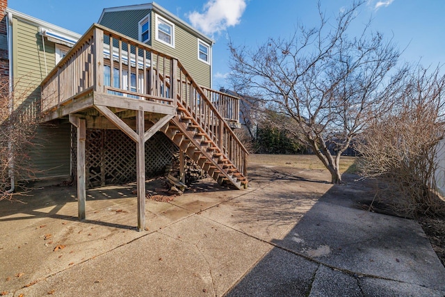 rear view of house featuring a deck, concrete driveway, and stairway