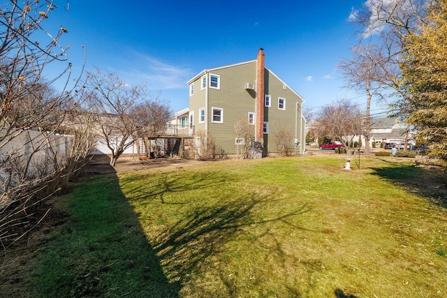 rear view of property with a chimney, fence, and a lawn