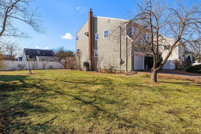 view of side of property featuring central AC unit, an attached garage, fence, a yard, and a chimney