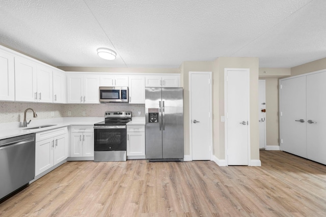 kitchen featuring light countertops, appliances with stainless steel finishes, light wood-type flooring, and a sink