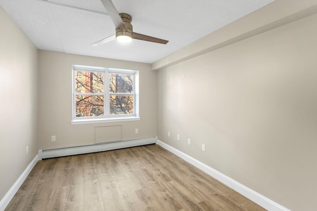 spare room featuring a baseboard heating unit, ceiling fan, light wood-style flooring, and baseboards