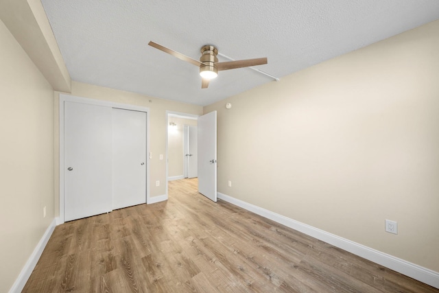 unfurnished bedroom with a textured ceiling, ceiling fan, wood finished floors, baseboards, and a closet