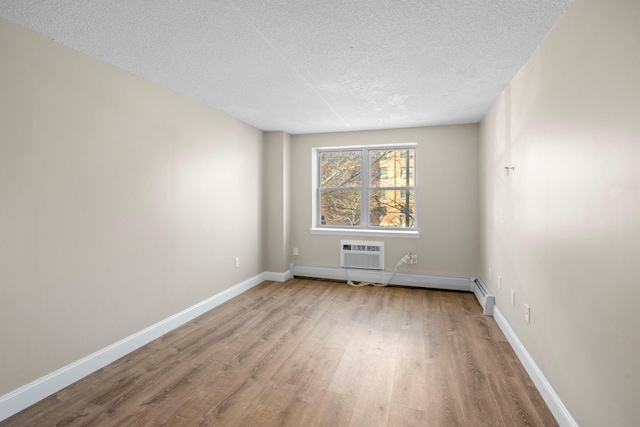 empty room with baseboards, wood finished floors, a textured ceiling, a baseboard heating unit, and a wall mounted AC