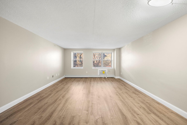 empty room with a textured ceiling, baseboards, and wood finished floors