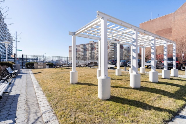 view of community with fence, a lawn, and a pergola