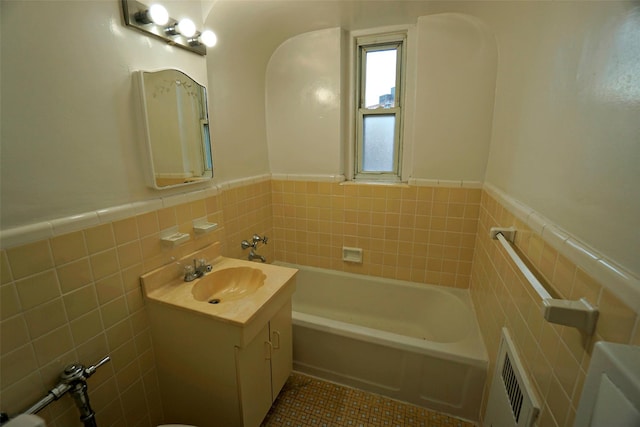 bathroom with tile patterned flooring, a wainscoted wall, vanity, tile walls, and a bathtub