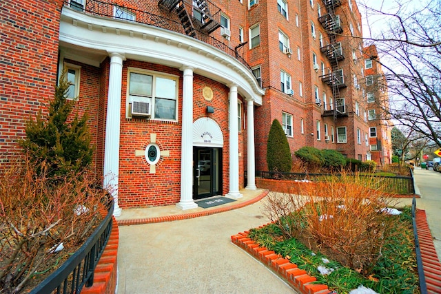 view of exterior entry featuring cooling unit and brick siding