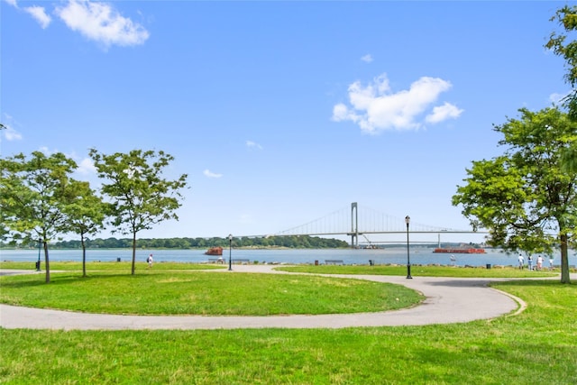 surrounding community with a water view and a lawn