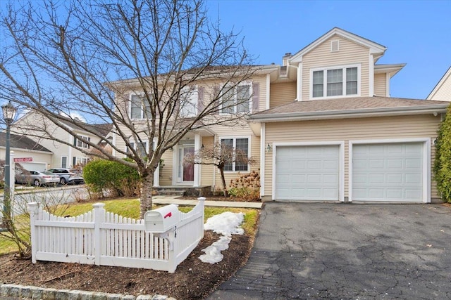 traditional-style home with fence, driveway, and an attached garage