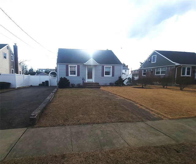 view of front of property featuring driveway, a front lawn, and fence