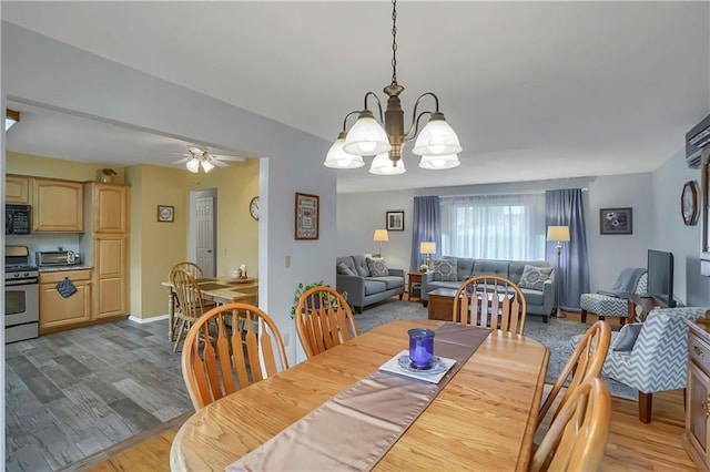 dining space featuring light wood-style flooring, a toaster, baseboards, and ceiling fan with notable chandelier