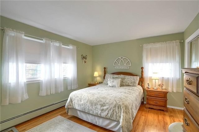 bedroom with light wood-type flooring, baseboards, and baseboard heating