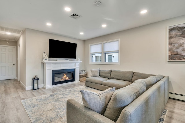 living room with light wood-style floors, attic access, and visible vents