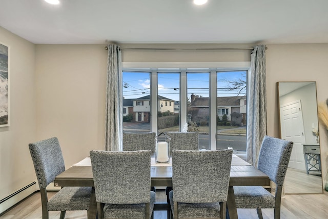 dining area featuring light wood-style flooring, plenty of natural light, and a baseboard radiator