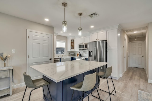 kitchen with white cabinetry, visible vents, stainless steel appliances, and a kitchen breakfast bar