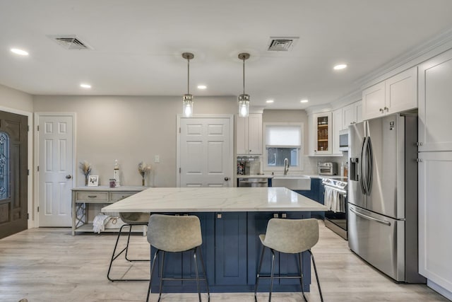 kitchen with stainless steel appliances, white cabinets, visible vents, and a kitchen bar