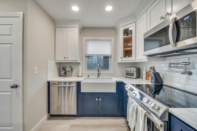 kitchen with stainless steel appliances, a sink, white cabinets, and blue cabinets