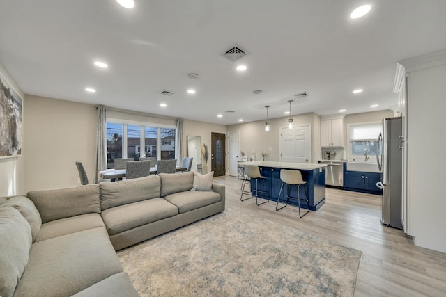 living area featuring visible vents, light wood-style flooring, and recessed lighting