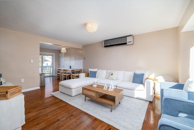 living area featuring baseboards, wood finished floors, and a wall mounted AC