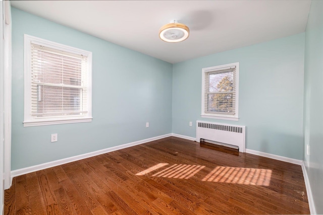 unfurnished room featuring baseboards, radiator heating unit, and wood finished floors