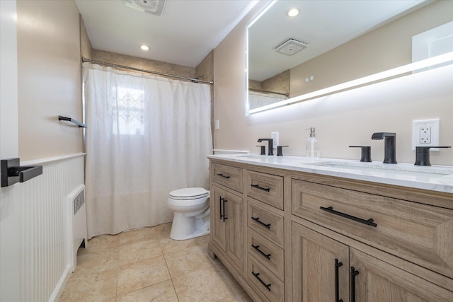 full bath featuring a wainscoted wall, double vanity, radiator, toilet, and a sink