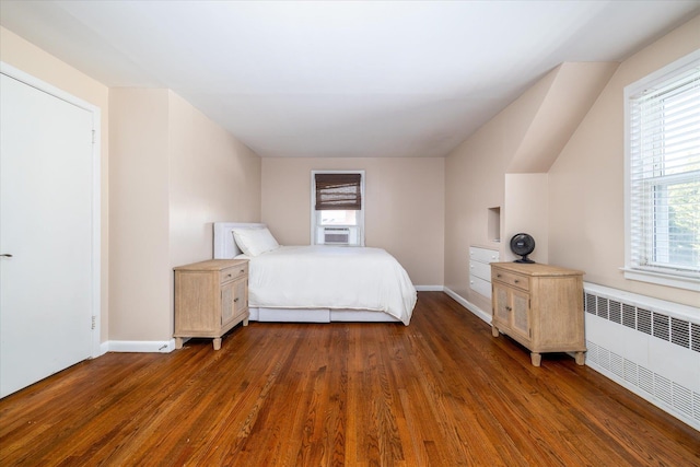 unfurnished bedroom featuring radiator, baseboards, cooling unit, and wood finished floors