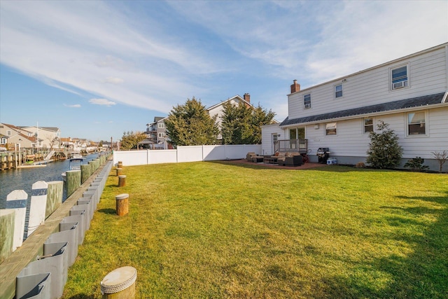 view of yard featuring a water view, a fenced backyard, and a residential view