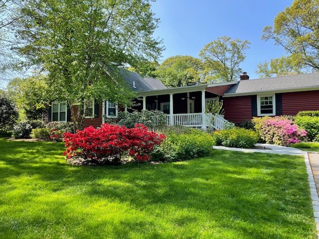 view of front of house with a porch, a chimney, and a yard