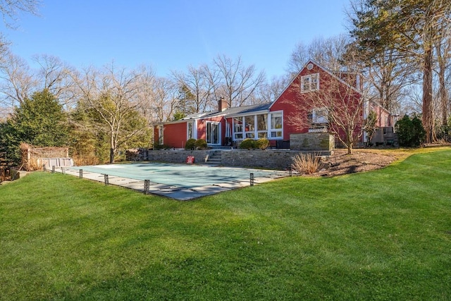 back of house featuring a chimney and a lawn